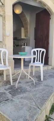 two white chairs and a table in front of a kitchen at Cottage Studio Zoe in Psematismenos
