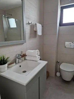 a white bathroom with a sink and a toilet at Kantara Beach Resort Apartment Olivia in Aglantzia