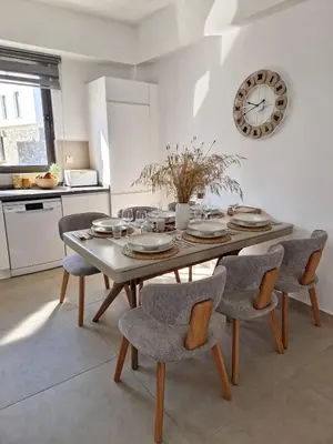a dining room table with chairs and a clock on the wall at Kantara Beach Resort Apartment Olivia in Aglantzia
