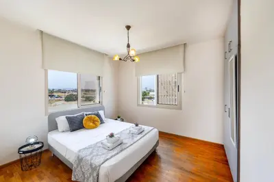 a bedroom with a large white bed and two windows at Mackenzie Beachfront Eftyhia Suite in Larnaka