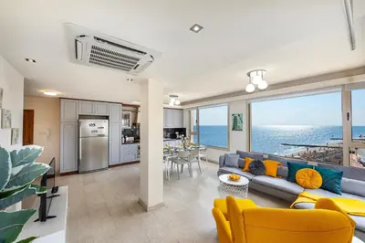 a living room with a blue couch and yellow chairs at Mackenzie Beachfront Eftyhia Suite in Larnaka
