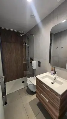 a bathroom with a sink and a toilet and a mirror at 1BR Serviced Apt with Pool & Premium Amenities in Voroklini