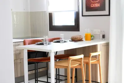 a small kitchen with a white table and chairs at 1BR Serviced Apt with Pool & Premium Amenities in Voroklini