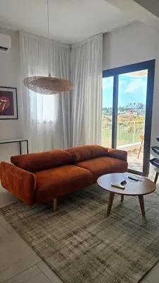 a living room with a brown couch and a table at 1BR Serviced Apt with Pool & Premium Amenities in Voroklini