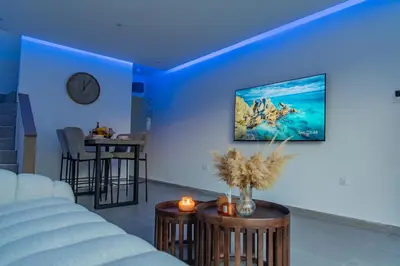 a blue room with a couch and a clock on the wall at TelMar White House - 100m from the Sea in Voroklini