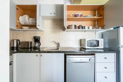 a kitchen with white cabinets and a sink and a microwave at Odin 1-BR Apartment & Balcony in Larnaca in Larnaka