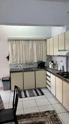a kitchen with white cabinets and a chair in it at Coast & City Apartment in Limassol