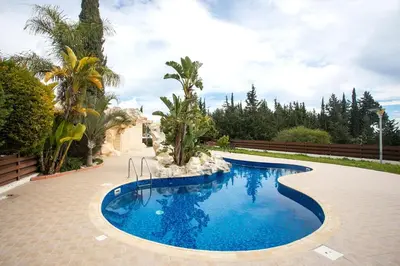 a swimming pool with blue water in a yard with trees at Modern & Fancy ground floor Studio - Pool & Relax in Tersephanou