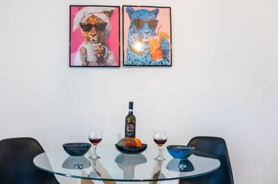 a table with two glasses of wine and three paintings at Modern & Fancy ground floor Studio - Pool & Relax in Tersephanou