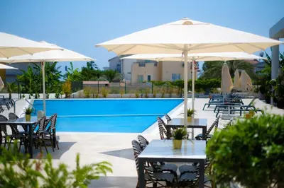 a patio with tables and umbrellas next to a pool at Panorama Comfort Suita in Protaras