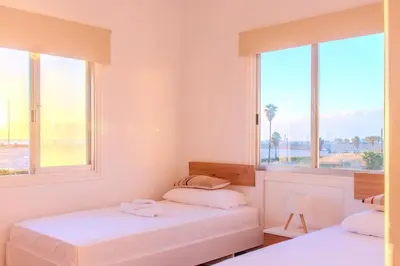 two beds in a room with two windows at TelMar Port Sea View - 10 minutes walk from Finikoudes in Larnaka