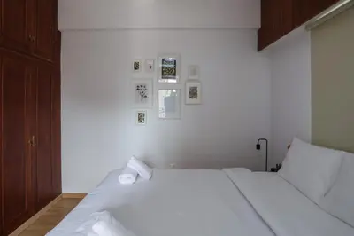 a white bed in a bedroom with pictures on the wall at Palmove Makenzy Charming 1Bed Apt in Larnaka