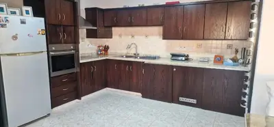 a kitchen with wooden cabinets and a white refrigerator at 3 Bedroom Penthouse Livadia Larnaca in Livadhia