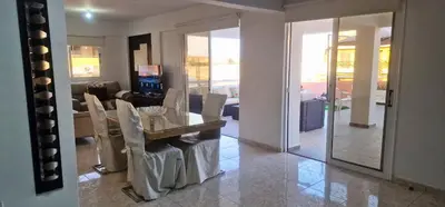 a dining room with a table and chairs and a living room at 3 Bedroom Penthouse Livadia Larnaca in Livadhia