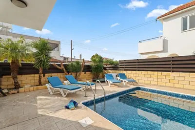 a swimming pool with blue chairs next to a house at Villa St George - 3 Bed Villa with Private Pool in Xylophaghou