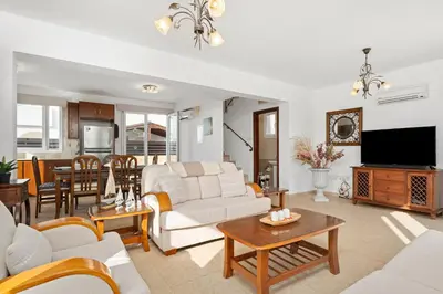 a living room with a white couch and a tv at Villa St George - 3 Bed Villa with Private Pool in Xylophaghou