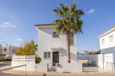 a white house with a palm tree in front of it at Protaras Villa Alina in Protaras