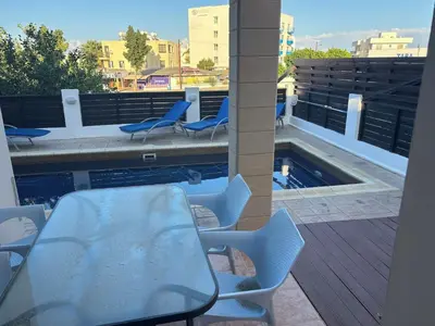a patio with a table and chairs next to a swimming pool at Pernera Sunrise Villa in Paralimni