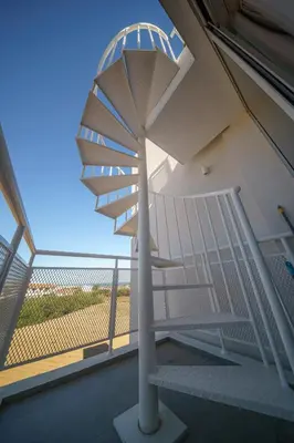 a spiral staircase in a building with a large window at Blue Horizon Seaview Suite with Rooftop and Pool in Paralimni in Paralimni