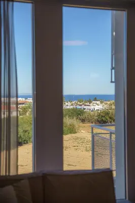 a view of the beach from a living room window at Blue Horizon Seaview Suite with Rooftop and Pool in Paralimni in Paralimni