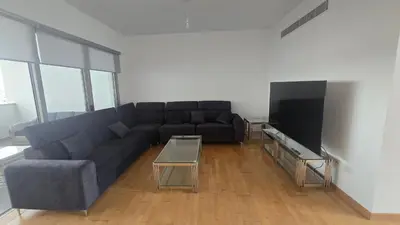a living room with a couch and a tv at Sea View Apartment Finikoudes in Larnaka