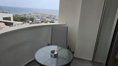 a glass table on a balcony with a view of a harbor at Sea View Apartment Finikoudes in Larnaka