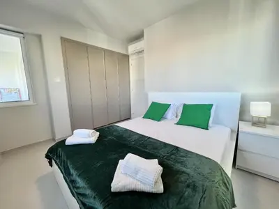 a bedroom with two white beds with green pillows at STAY Atalanta Apartment in Larnaka