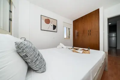 a bedroom with a white bed with a wooden cabinet at 1 bedroom flat in Nicosia