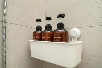 four bottles of alcohol sitting on a shelf in a bathroom at 1 bedroom flat in Nicosia