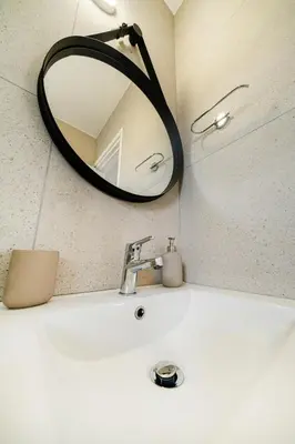a bathroom sink with a round mirror above it at 1 bedroom flat in Nicosia