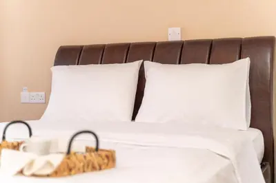 a bed with white pillows and a basket on it at Seafront 1 bedroom flat in Limassol