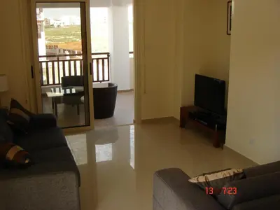 a living room with a couch and a television at 2 Bed apartment with huge balcony overlooking pool in Paralimni