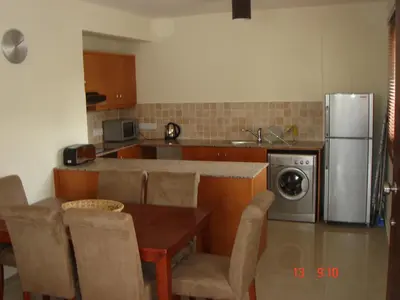 a kitchen with a table and a stainless steel refrigerator at 2 Bed apartment with huge balcony overlooking pool in Paralimni
