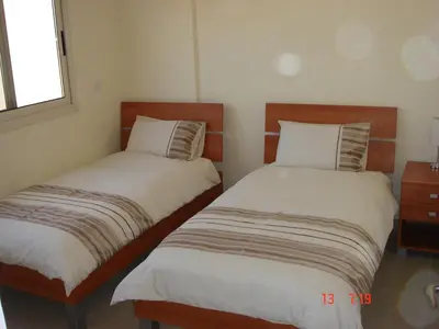two twin beds in a room with a window at 2 Bed apartment with huge balcony overlooking pool in Paralimni