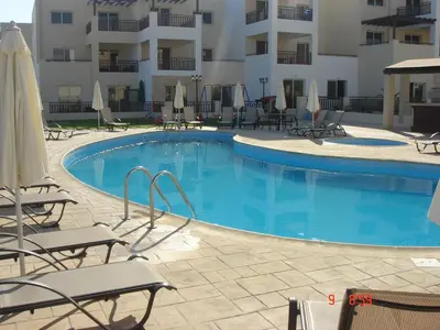 a swimming pool in a hotel with chairs and umbrellas at 2 Bed apartment with huge balcony overlooking pool in Paralimni