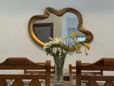 a vase of flowers on a table in front of a mirror at Bella's Place - Stylish 2BD With large Veranda in Larnaka