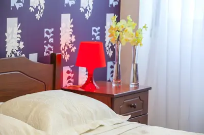 a bedroom with a red lamp on a table with flowers at Omerou Apartment in Nicosia