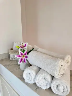 a bunch of towels on a counter with a vase of flowers at Modern 2BR Villa with Heated Hot Tub and Steps to Beach in Paralimni