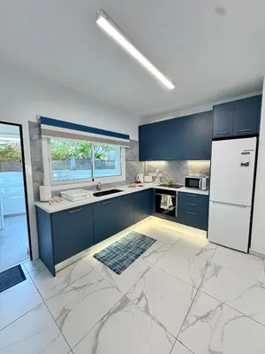 a kitchen with blue cabinets and a white refrigerator at Modern 2BR Villa with Heated Hot Tub and Steps to Beach in Paralimni