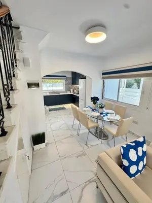 a kitchen and living room with a table and chairs at Modern 2BR Villa with Heated Hot Tub and Steps to Beach in Paralimni