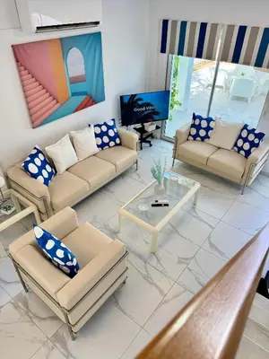 a living room with couches and a table and a tv at Modern 2BR Villa with Heated Hot Tub and Steps to Beach in Paralimni