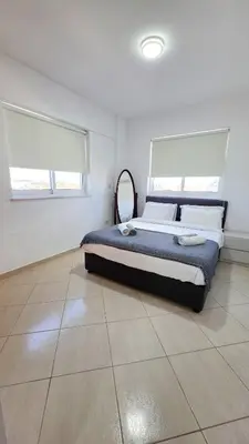 a bedroom with a large bed in a white room at Sunset Poolside Apartment with Pool facility in Larnaka