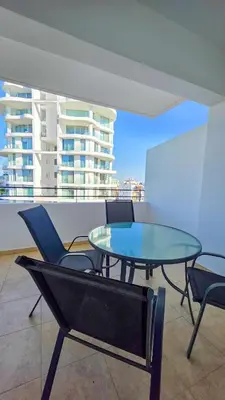 a glass table and chairs on top of a building at Sunset Poolside Apartment with Pool facility in Larnaka