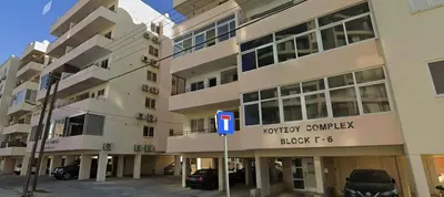 a building with a parking lot in front of it at Sunset Poolside Apartment with Pool facility in Larnaka
