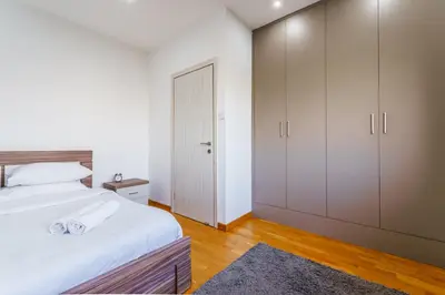 a bedroom with a large white bed and cabinets at Fam Glam Comfort Apartment in Larnaka