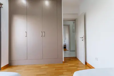 a bedroom with white cabinets and wooden floors at Fam Glam Comfort Apartment in Larnaka