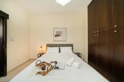 a bedroom with a white bed with a wooden cabinet at 1 bedroom flat near center in Nicosia