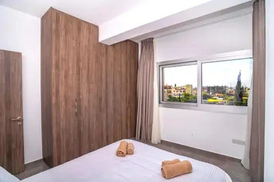 a bedroom with a bed and a large window at Celeste Suites in Limassol
