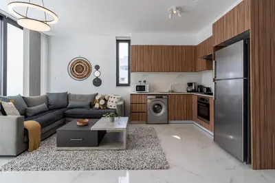 a living room with a couch and a kitchen at Taupe's 2-BR Apartment & Balcony in Larnaca in Livadhia