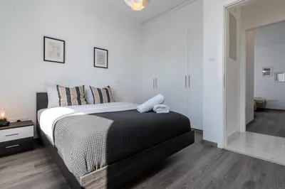 a bedroom with a large bed with white walls at Taupe's 2-BR Apartment & Balcony in Larnaca in Livadhia